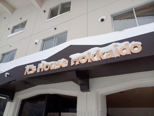 a sign on top of a building with snow on it at K's House Hokkaido - Asahidake Onsen Hostel in Higashikawa
