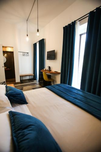 a bedroom with a bed with blue curtains and a desk at Luna Federiciana Luxury Room & Spa in Altamura