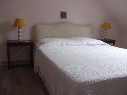 a bedroom with a white bed with two lamps on tables at Penty de Kervillerm in Douarnenez
