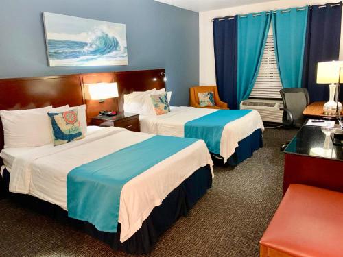 two beds in a hotel room with blue curtains at Hotel Pensacola in Pensacola