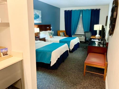 a hotel room with two beds and a desk and a chair at Hotel Pensacola in Pensacola