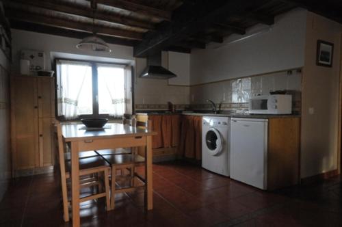 cocina con mesa y lavadora en Apartamentos Rurales Romallande en Puerto de Vega