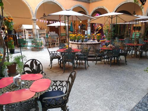 un patio al aire libre con mesas, sillas y sombrillas en Casa Relox 23, en San Miguel de Allende