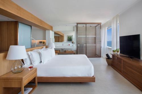 um quarto com uma grande cama branca e uma televisão em JANEIRO Hotel no Rio de Janeiro