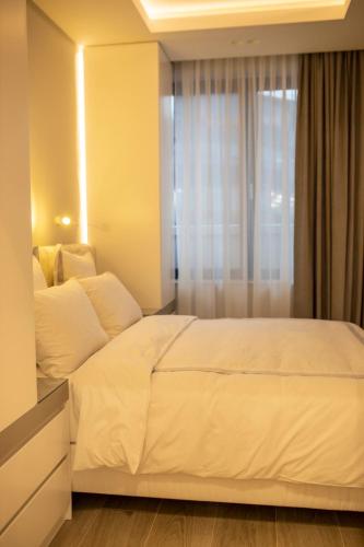 a bedroom with a white bed and a window at Pupin Palace Apartments in Novi Sad