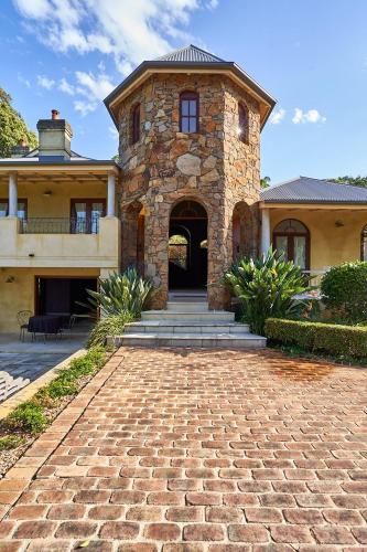 a large stone house with a brick driveway at Victoria's At Ewingsdale in Byron Bay