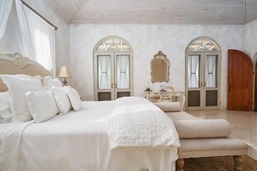 a white bedroom with a large bed and two windows at Victoria's At Ewingsdale in Byron Bay