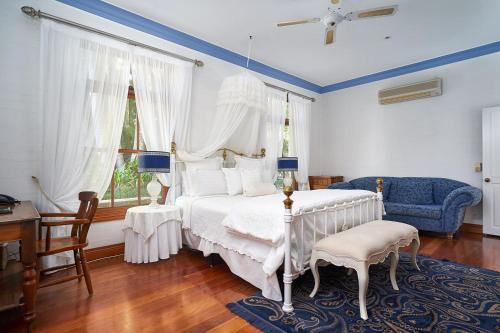 a bedroom with a white bed and a blue chair at Victoria's At Ewingsdale in Byron Bay