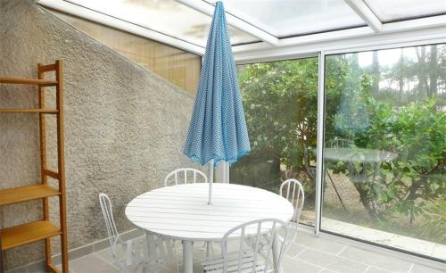 une table blanche avec des chaises et un parapluie bleu dans l'établissement Réf 271, Seignosse Océan, Villa Patio au calme sous les pins, à quelques minutes de la plage et des commerces, 5 personnes, à Seignosse