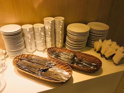 a table with plates and utensils and stacks of dishes at Primme Hotel Aracaju in Aracaju