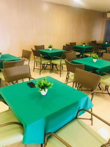 a room with green tables and chairs with plants on them at Primme Hotel Aracaju in Aracaju
