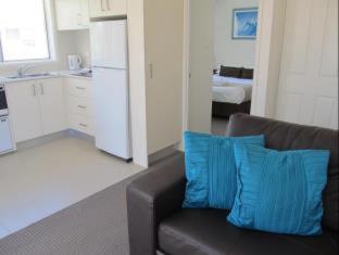 a living room with a brown couch with blue pillows at Costa D'Ora Holiday Apartments in Gold Coast