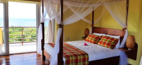 a bedroom with a canopy bed and a large window at Kaye Mango in Soufrière