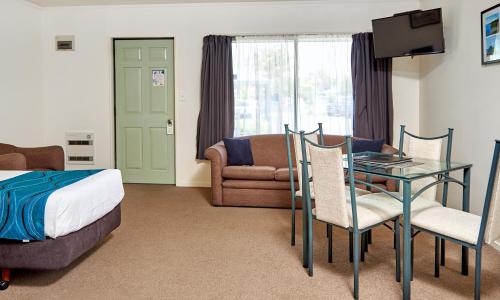 ein Hotelzimmer mit einem Bett und einem Glastisch in der Unterkunft Barringtons Motor Lodge in Whakatane