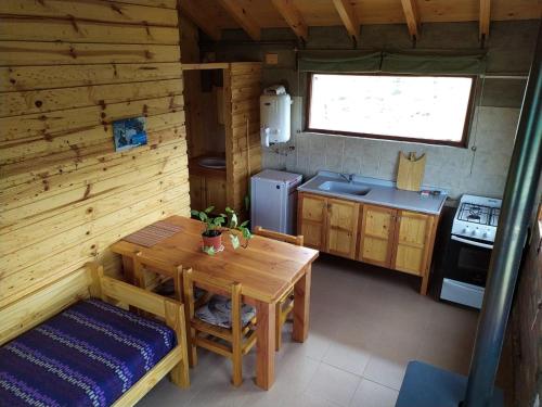 cocina con mesa de madera, mesa y fogones en Cabañas Müller en Lago Huechulafquen