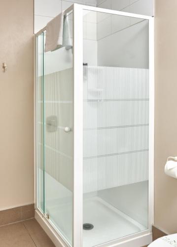 a shower with glass doors in a bathroom at Barringtons Motor Lodge in Whakatane