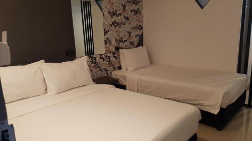 two beds in a hotel room with white sheets at Loyy Hotel in Chiang Mai