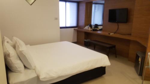 a bedroom with a bed and a desk and a television at Loyy Hotel in Chiang Mai