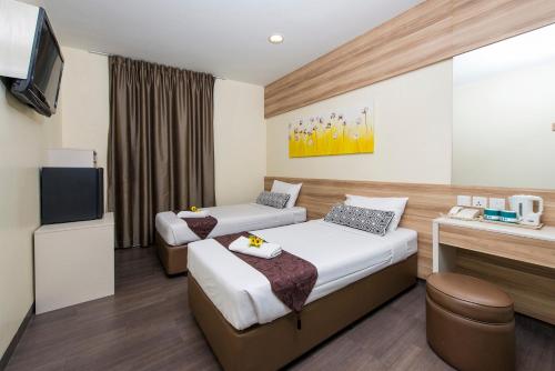 um quarto de hotel com duas camas e uma televisão em Hotel 81 Dickson em Singapura