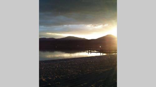 a sunset on the shore of a body of water at Tongariro Adventures The Lodge in Kuratau