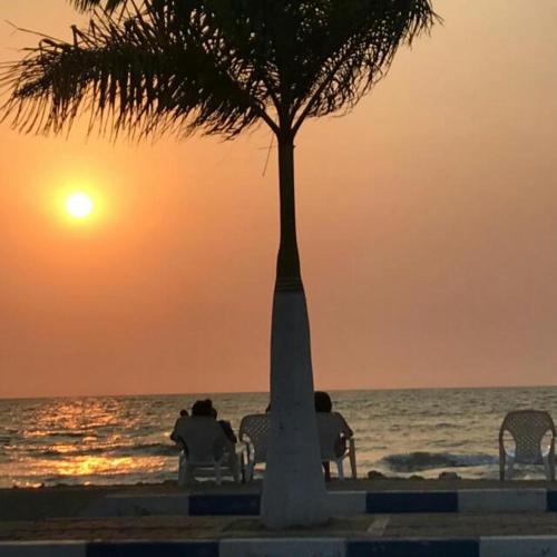two people sitting on chairs watching the sunset on the beach at Hotel Don Toño Tolú in Tolú