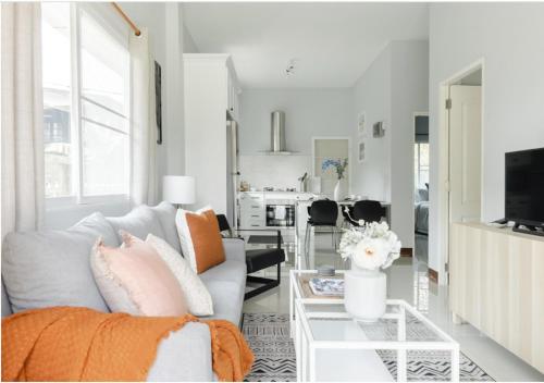 a white living room with a couch and a table at Chiang Mai Jasmine Cottage in Chiang Mai