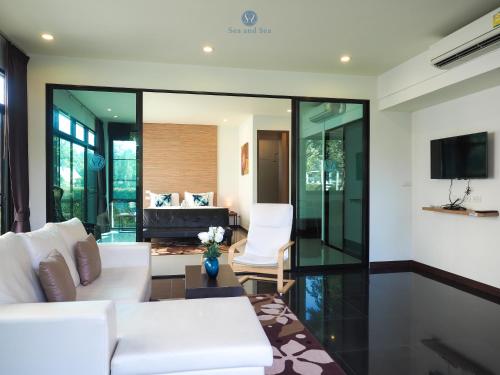 a living room with a white couch and a tv at Sea and Sea Villa Sangaroon in Ban Nam Tok