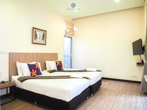 two beds in a hotel room with a tv at Sea and Sea Villa Sangaroon in Ban Nam Tok