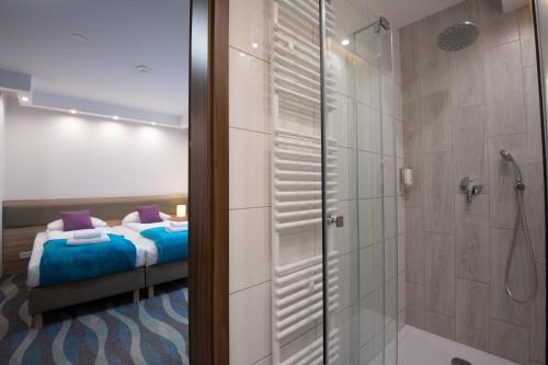 a bathroom with a bed and a shower with a glass door at Hotel Bardo in Bardo