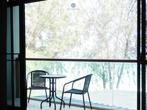 two chairs and a table in front of a window at Sea and Sea Villa Sangaroon in Ban Nam Tok