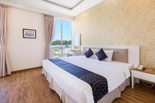 - une chambre avec un grand lit et une grande fenêtre dans l'établissement Capital O 585 Saigon Book Da Lat Hotel, à Đà Lạt