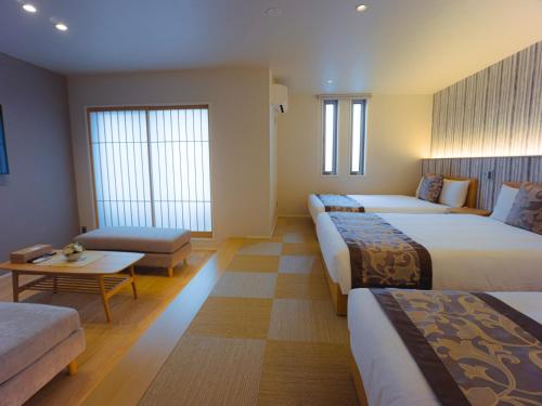 um quarto de hotel com três camas e um sofá em GRAND BASE Hakata Sumiyoshi em Fukuoka