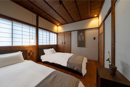 1 dormitorio con 2 camas y ventana en Kurohoro Machiya House en Kanazawa