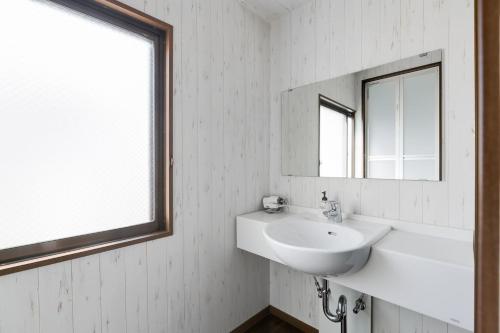 a white bathroom with a sink and a mirror at Liz5 Guest House Liz Nakazakicho in Osaka