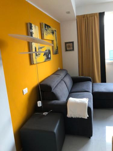 a living room with a blue couch and yellow wall at Hotel CineApollo - Ogni camera un film! in Messina