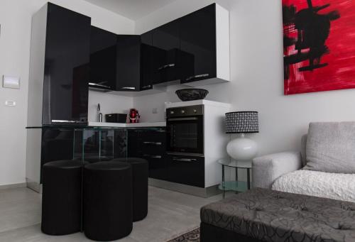a living room with a kitchen with black cabinets at Hotel CineApollo - Ogni camera un film! in Messina