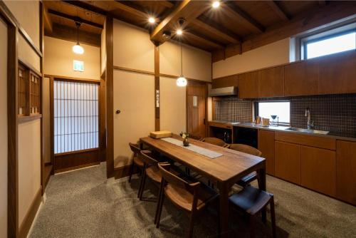 a kitchen with a wooden table and some chairs at Kurohoro Machiya House in Kanazawa