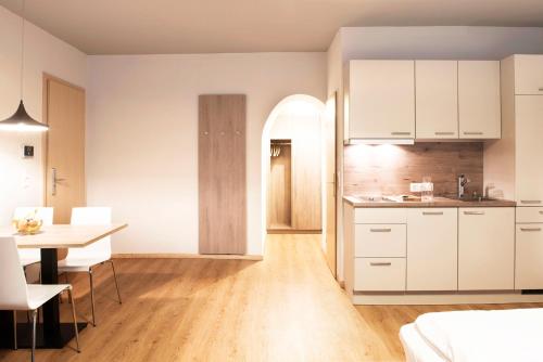 cocina y comedor con armarios blancos y mesa en Daxburg Apartments en Innsbruck