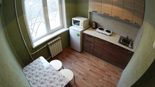 una pequeña cocina con fregadero y nevera. en Apartments on Prospekt Dimitrova, en Novosibirsk