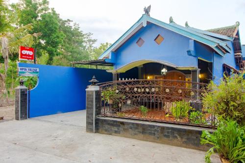 een blauw huis met een hek ervoor bij OYO 2047 Opak Village Bed & Breakfast in Bantul