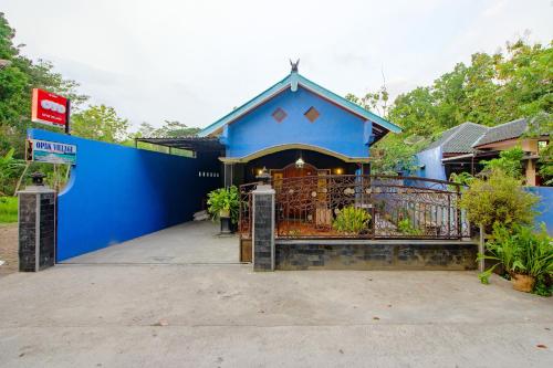 a blue house with a gate and a building at OYO 2047 Opak Village Bed & Breakfast in Bantul