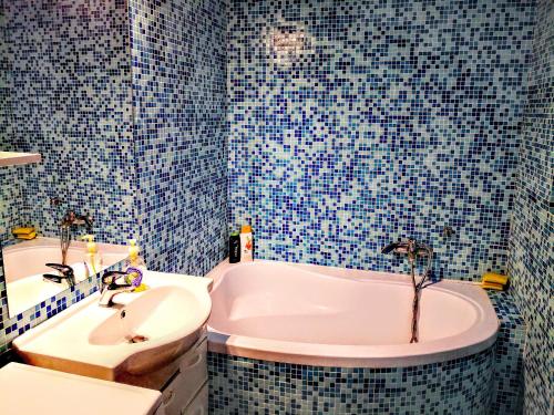 ein blau gefliestes Bad mit einer Badewanne und einem Waschbecken in der Unterkunft Relaxing & Welcome Apartment, Ared, UTA - All Inclusive in Arad