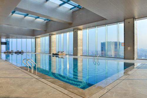 a swimming pool in a building with a view of the city at Pullman Huizhou Kaisa in Huizhou