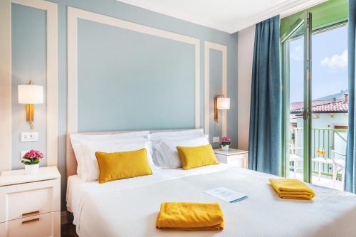 1 dormitorio con 1 cama blanca grande con almohadas amarillas en Sky Pool Hotel Sole Garda, en Garda