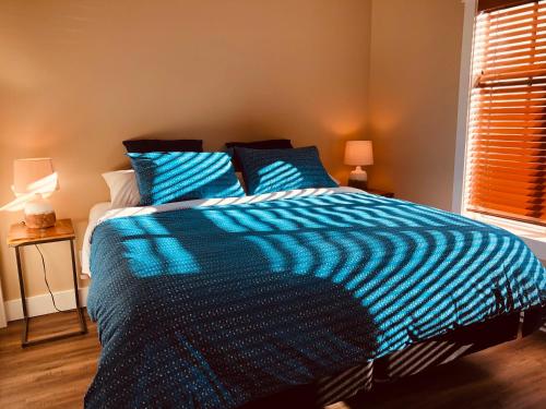 a blue and white bed in a bedroom with a window at Botany Bay by Eagle Reach Properties in Port Renfrew