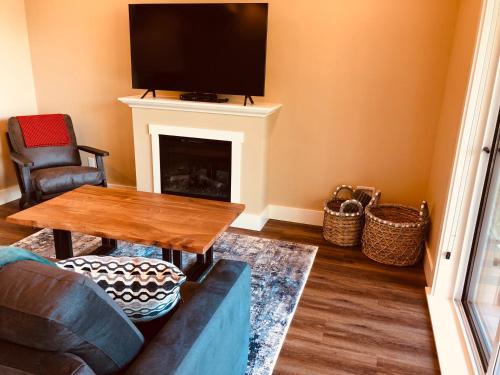 a living room with a couch and a table and a fireplace at Botany Bay by Eagle Reach Properties in Port Renfrew