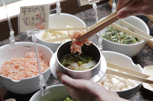 a person is holding a bowl of food with chopsticks at Tokachigawa Onsen Daiichi Hotel in Otofuke