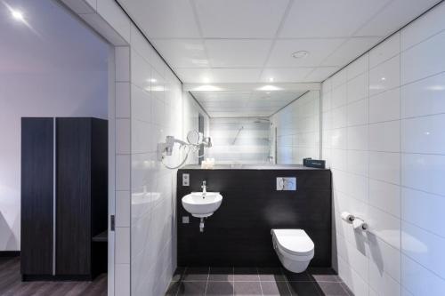 a white bathroom with a sink and a toilet at Postillion Hotel Dordrecht in Dordrecht