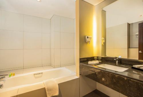 Swiss-Belhotel Bogor في بوغور: حمام مع حوض ومغسلة ومرآة