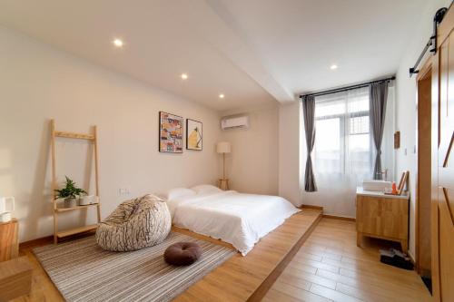 a bedroom with a white bed and a large window at Wander Hostel in Haikou